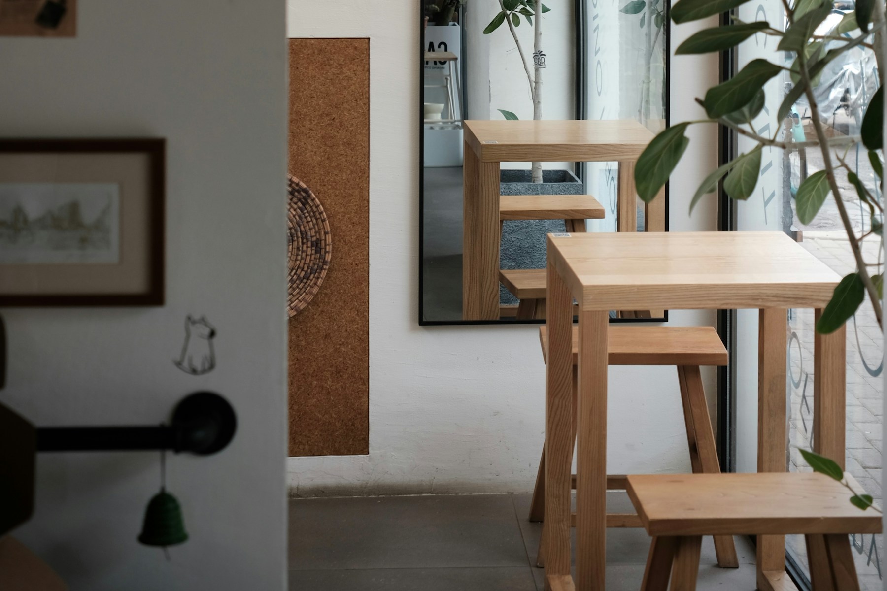 木のテーブルと植物が並ぶ、光の入るカフェ店内