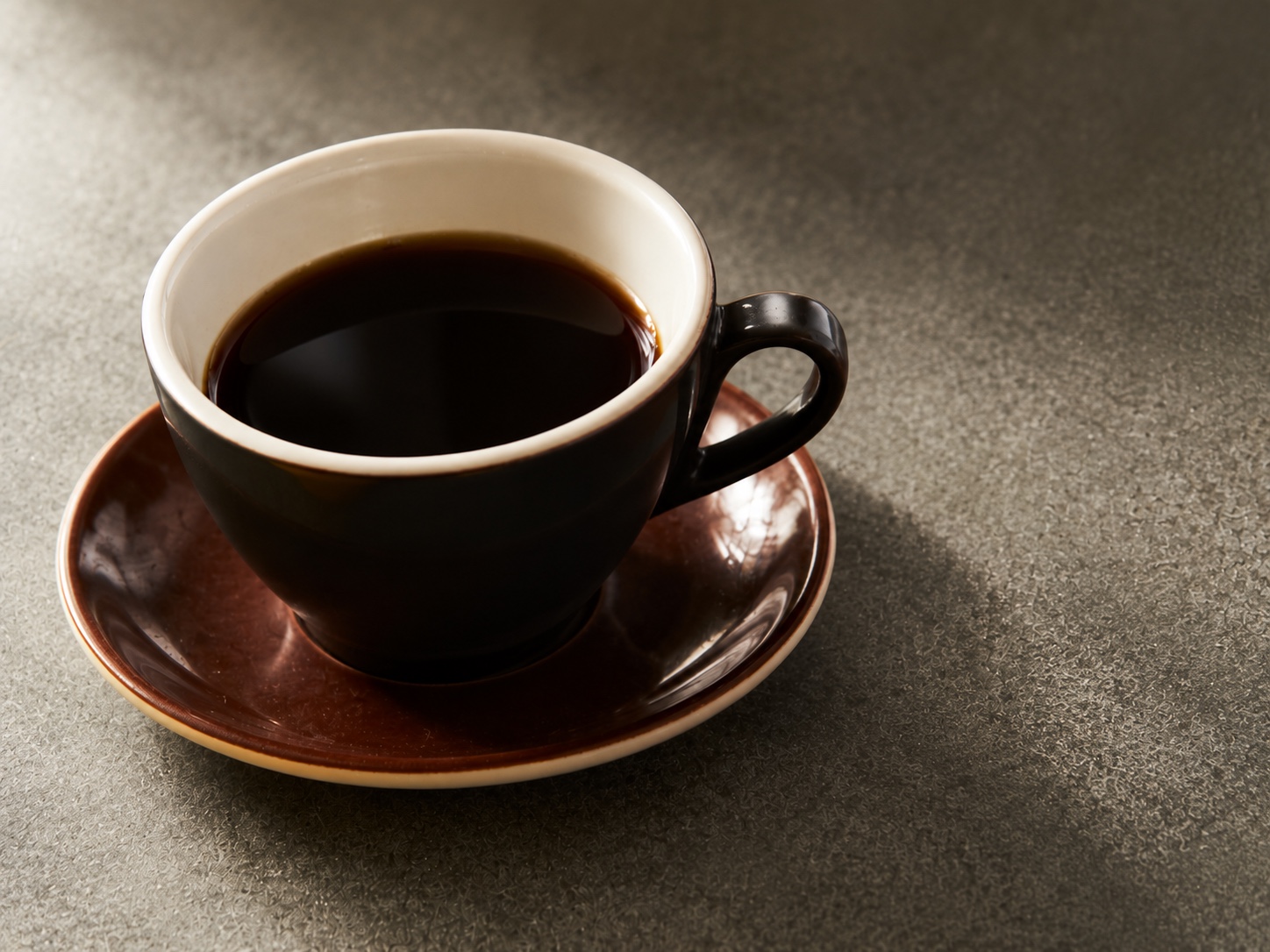 黒いカップの余白ブレンドと赤茶色のソーサー